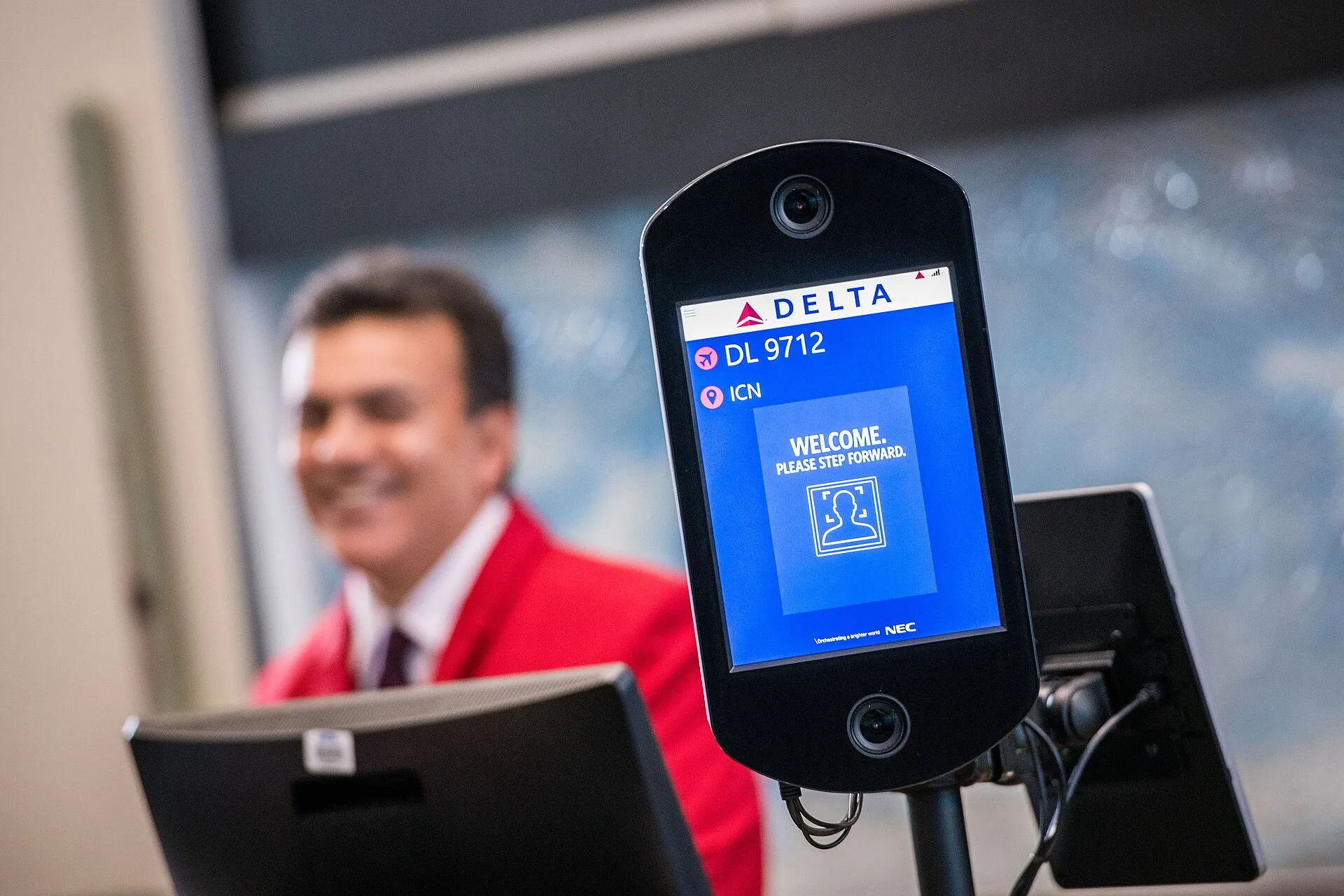 A biometric face-scanning kiosk reading 'Welcome. Please step forward.'