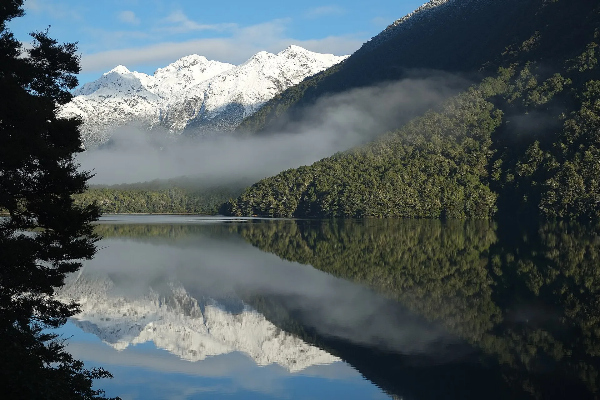 Snow-capped peaks reflected in a perfectly still lake on a winter morning