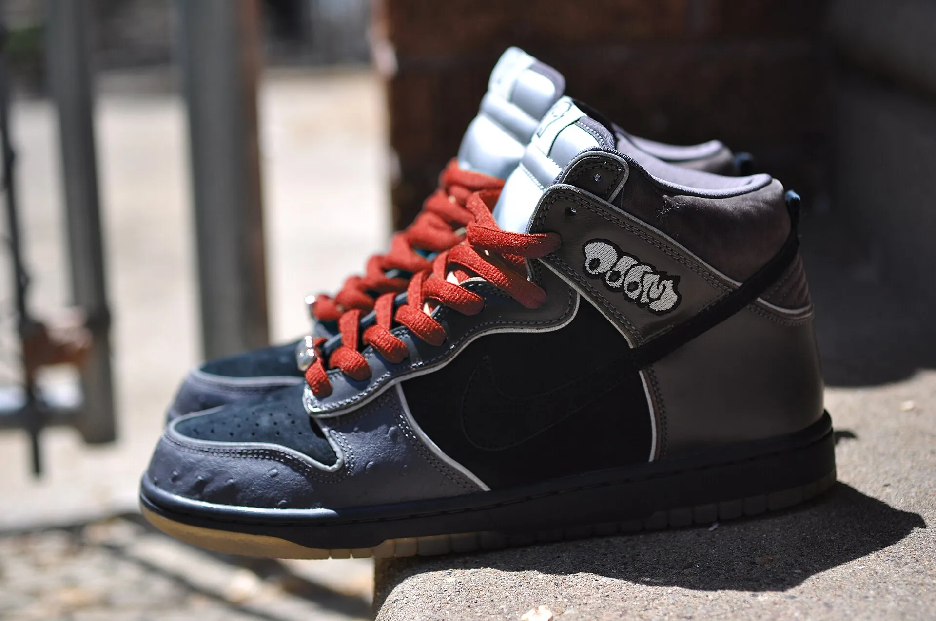 A Nike SB Dunk High sneaker photographed in profile on a kerb