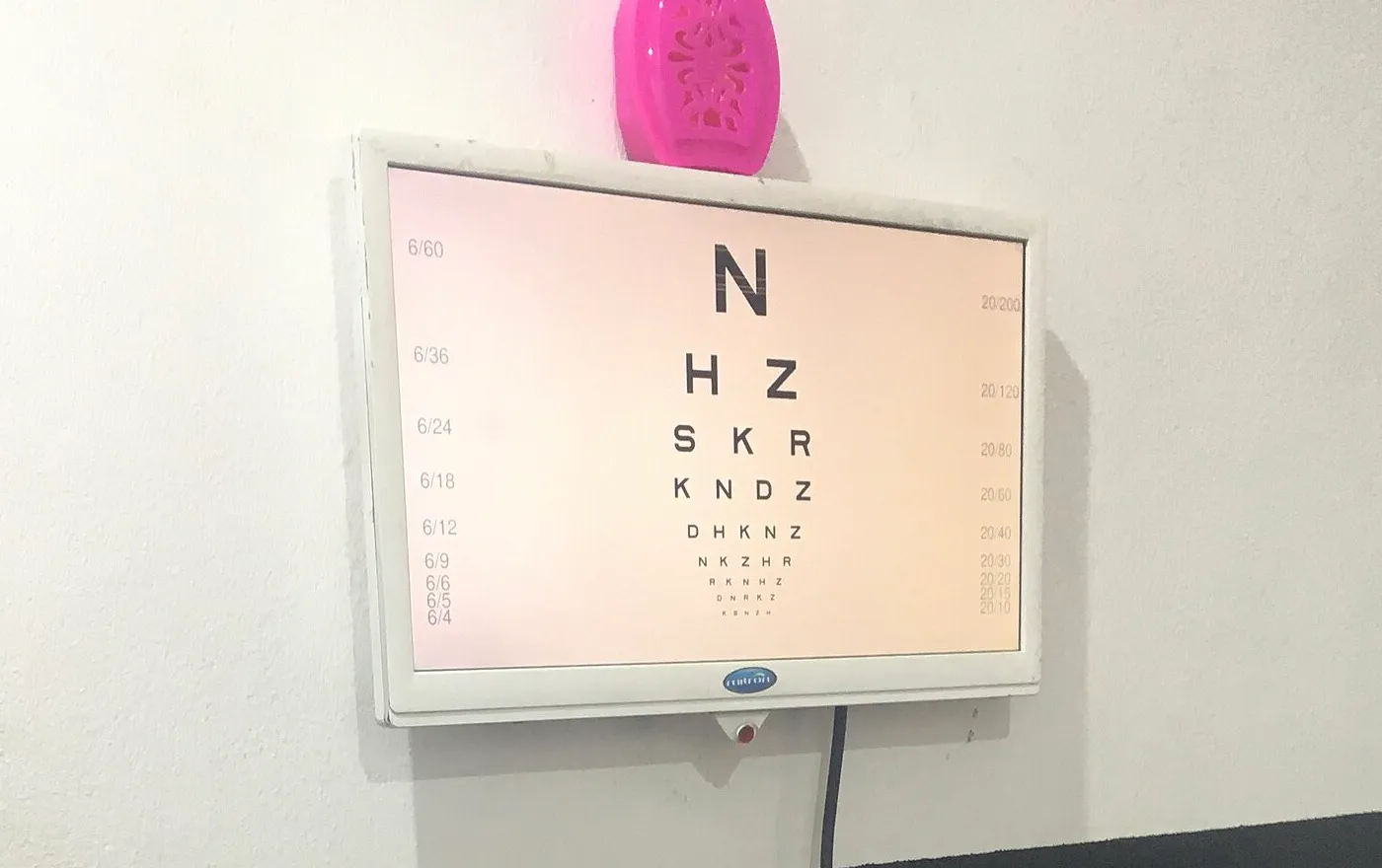 A backlit Snellen eye chart mounted on a clinic wall