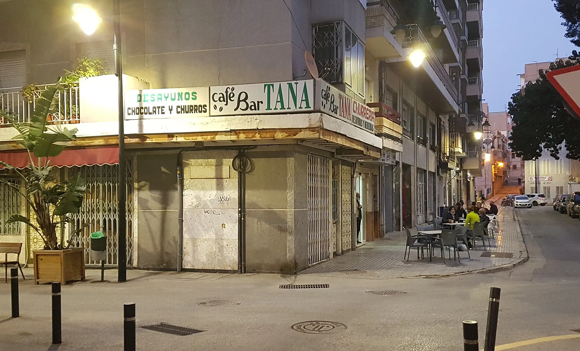 A corner café-bar in Spain at dusk, a few tables out on the terrace