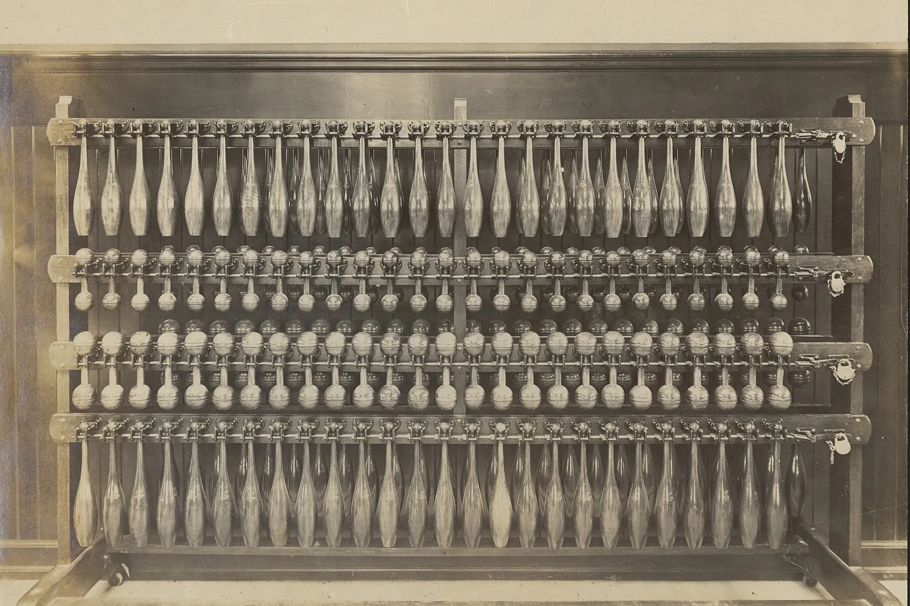 A rack of Indian clubs and dumbbells in four rows, from a 1904 model gymnasium exhibit